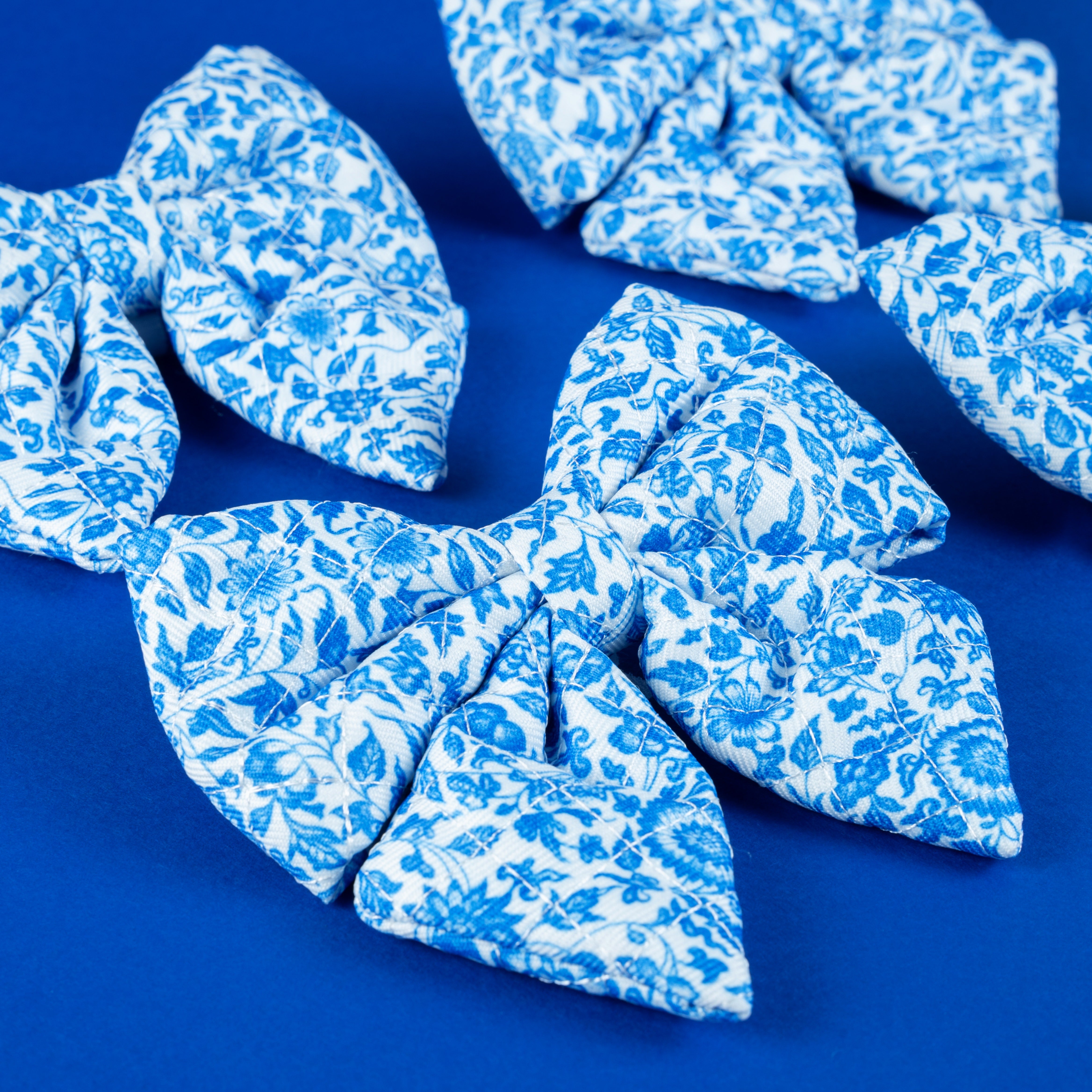 Blue floral patterned dog bow ties on vibrant blue background, stylish pet accessories for small dogs