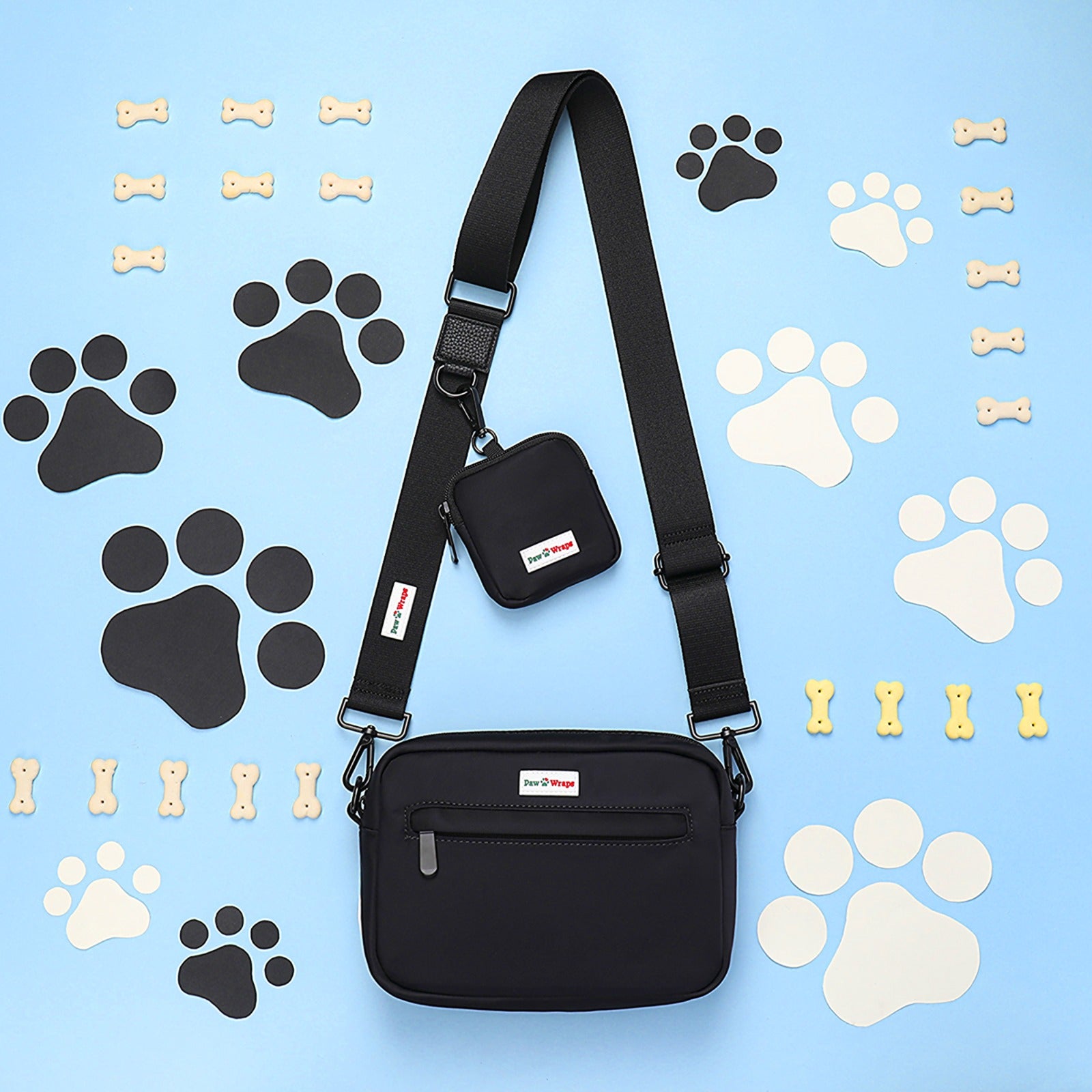 Stylish black dog walking bag with matching pouch, surrounded by paw prints and bones on blue background