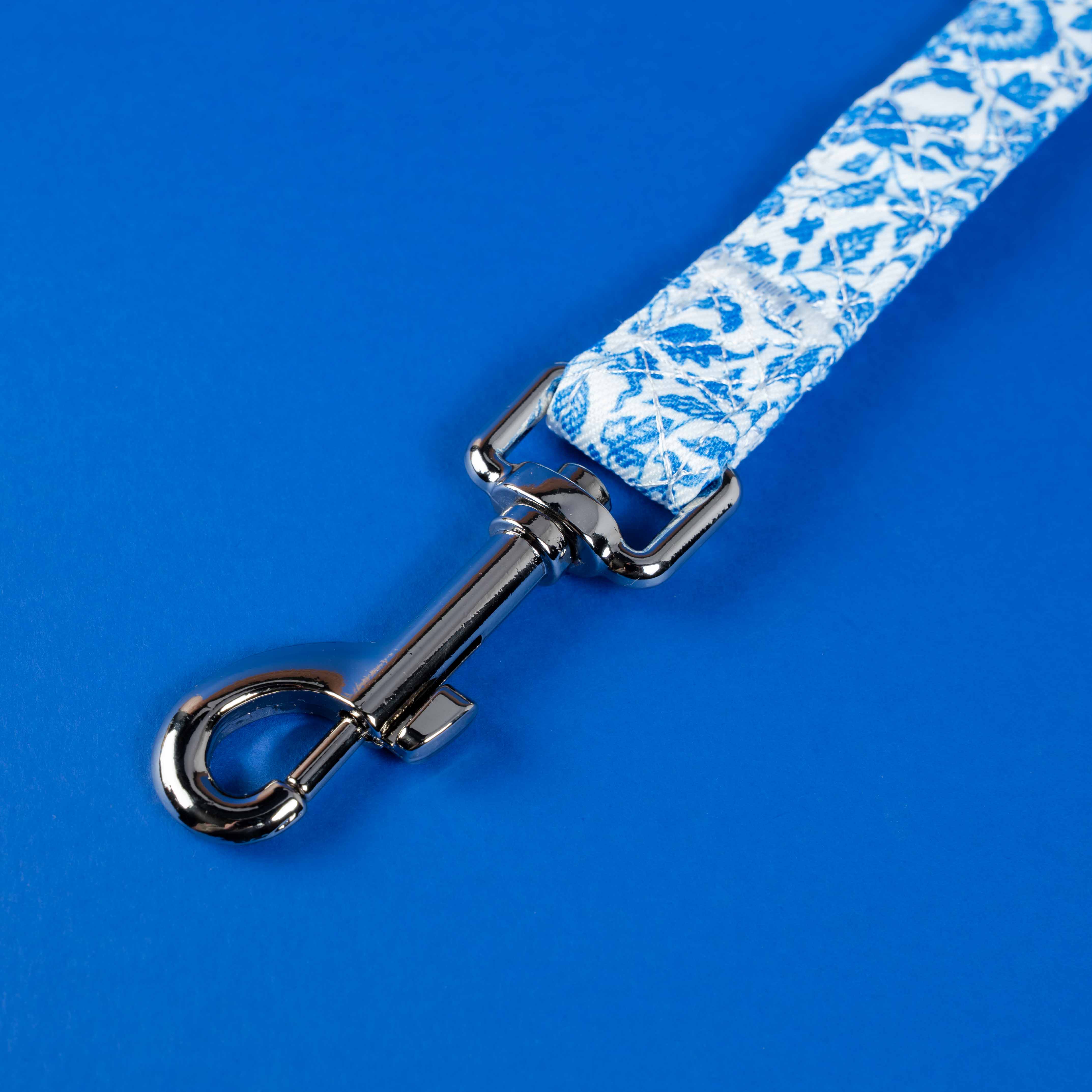 Blue floral dog leash with chrome clip on vibrant blue background