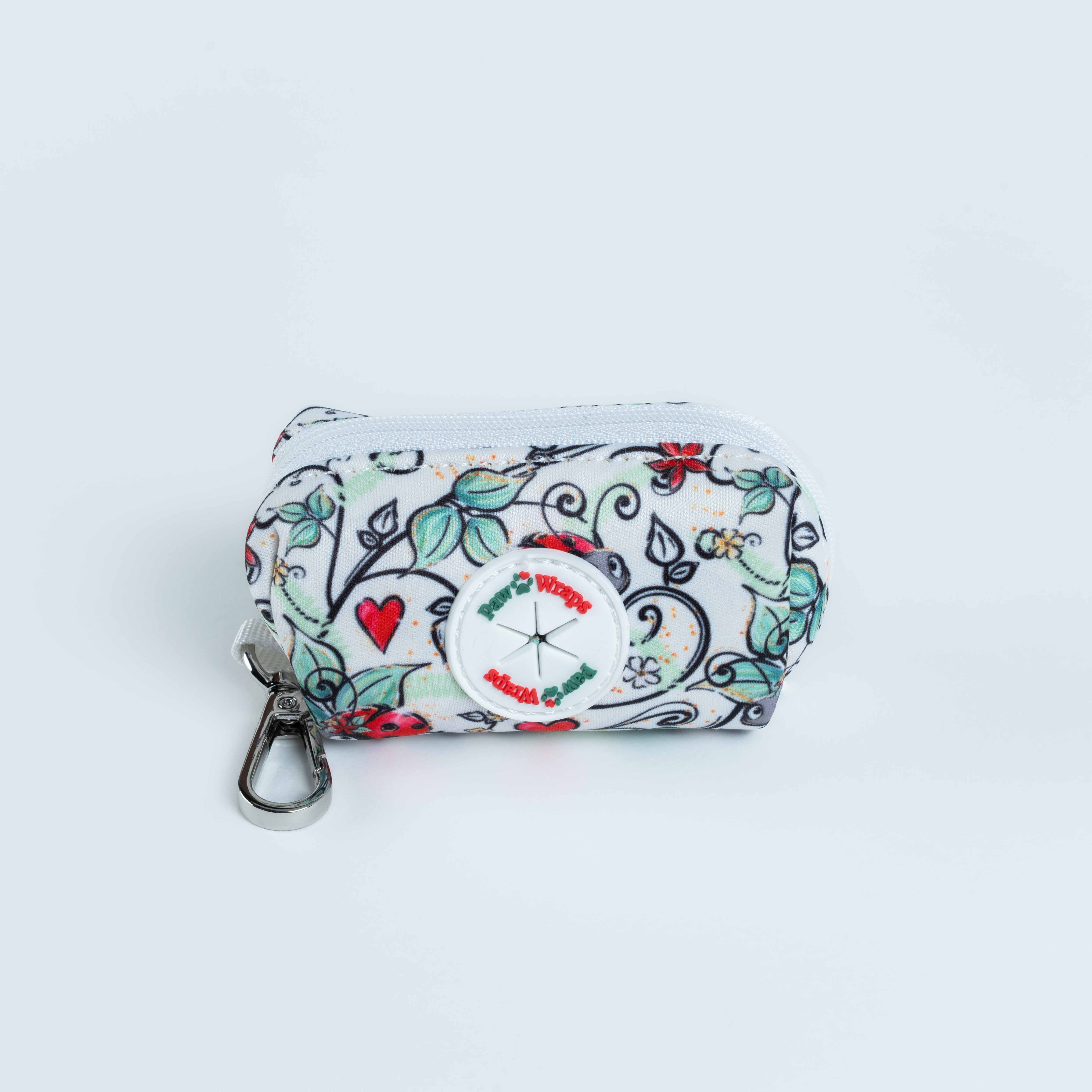 Floral print dog poop bag dispenser with hearts, ladybugs, and a clip for easy attachment to leashes or belts.