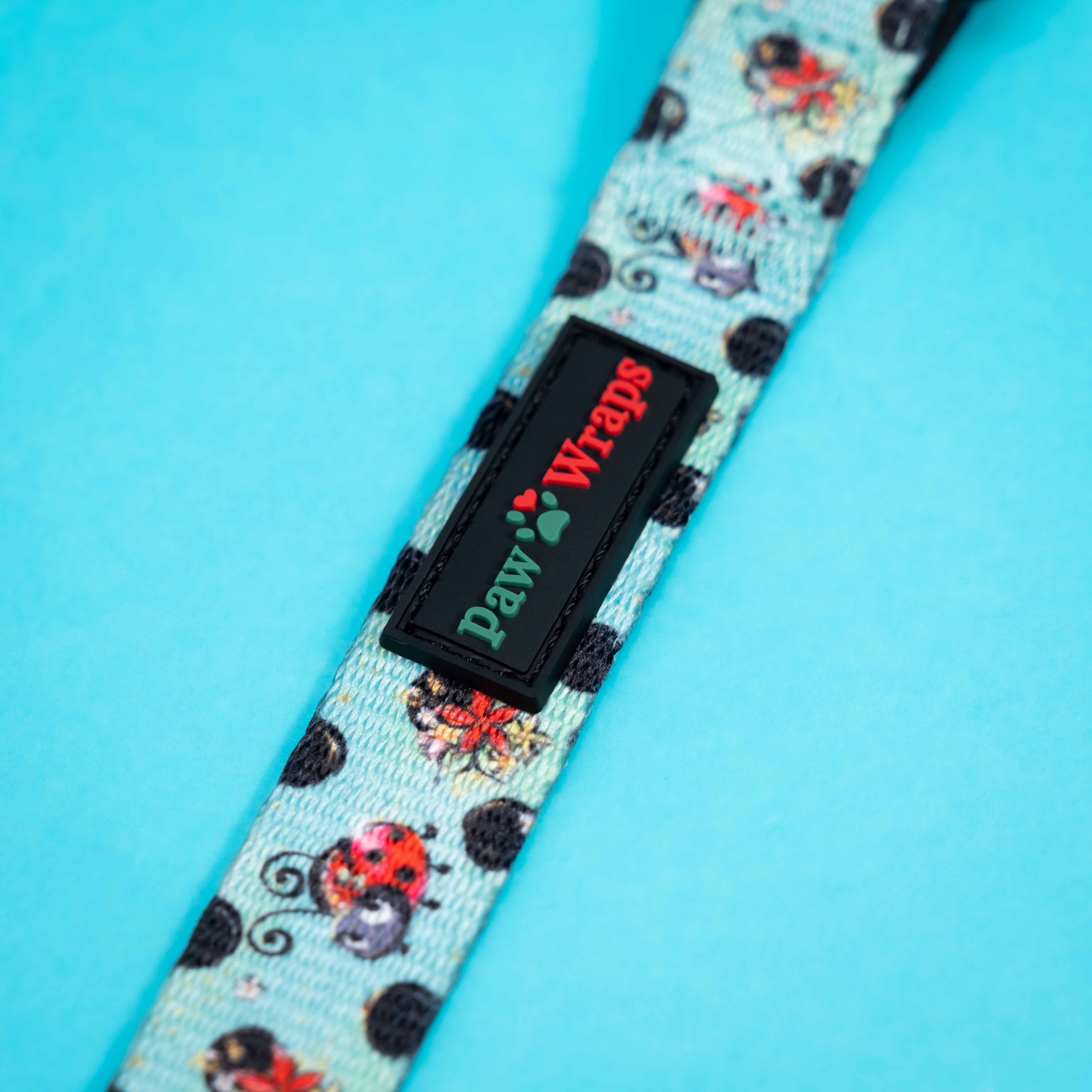Paw Wraps dog leash with ladybug print and brand tag on blue background