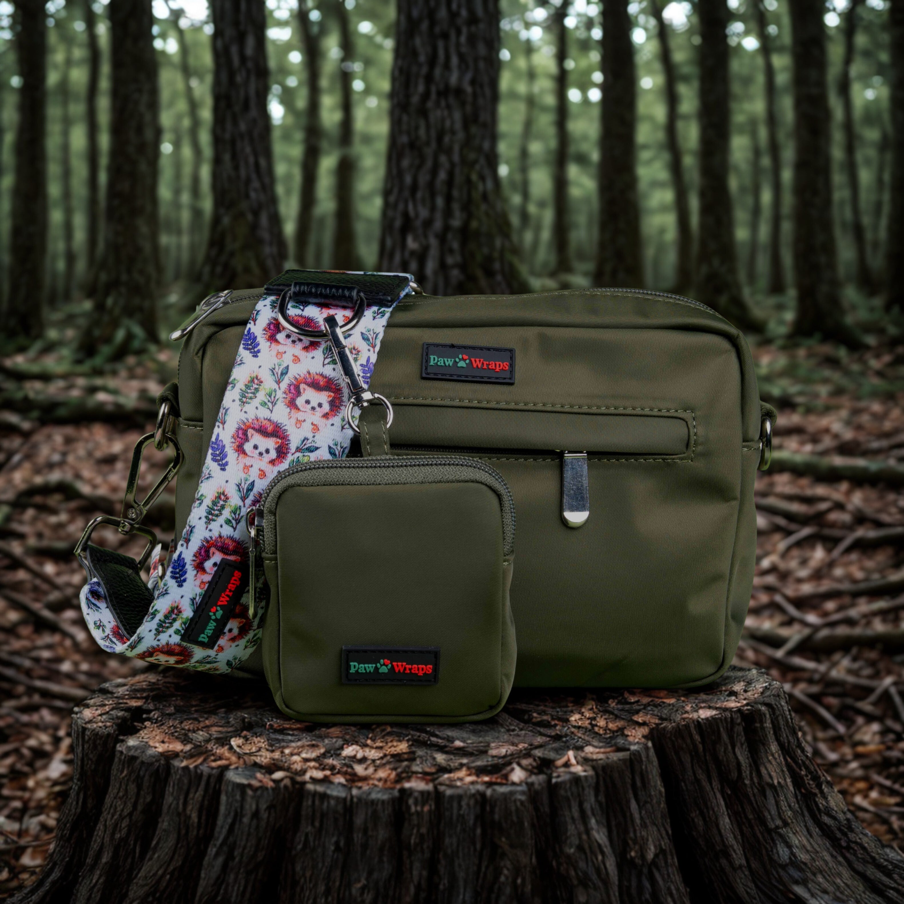 Olive green dog walking bag with floral hedgehog strap, set in forest on tree stump, perfect for stylish pet walks.