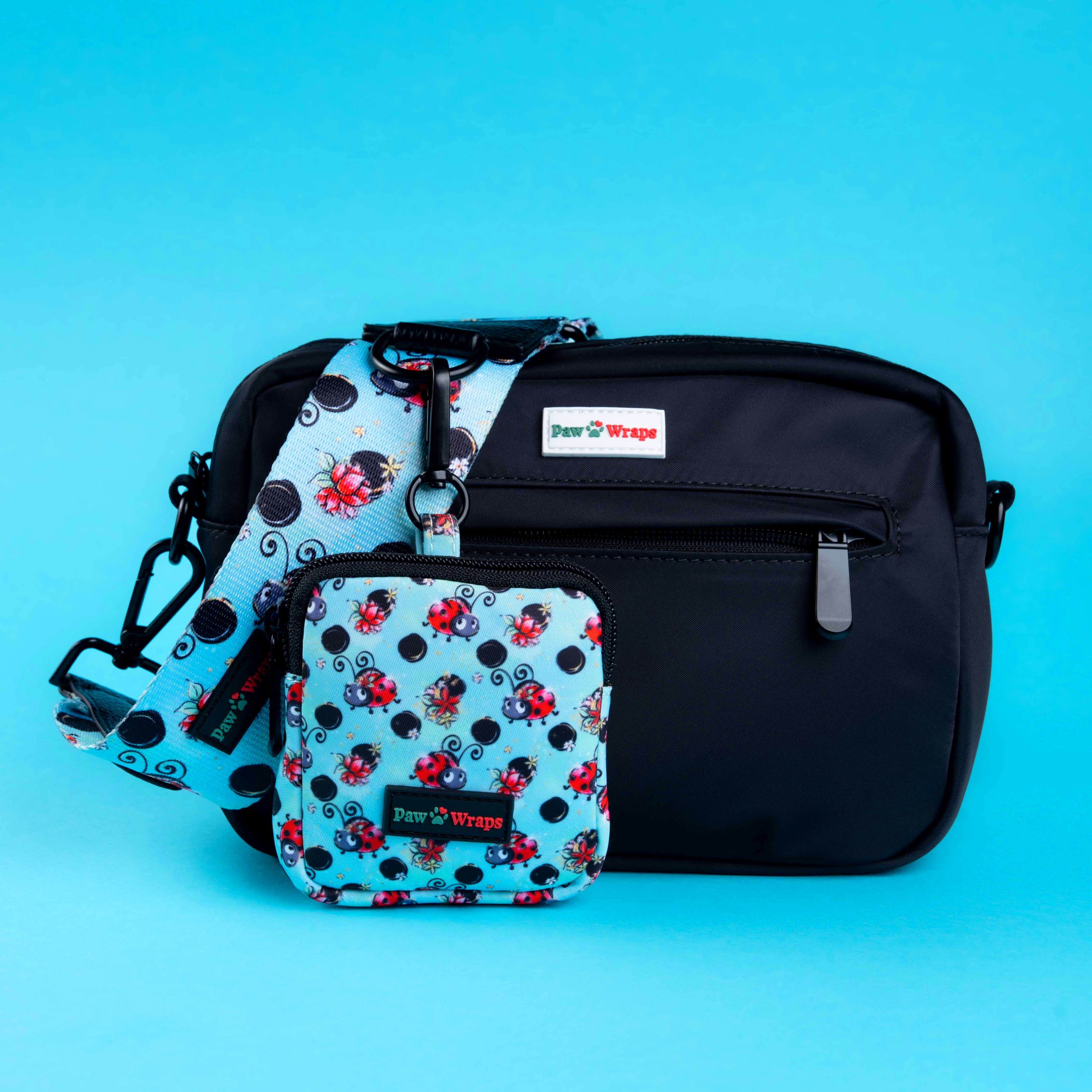 Stylish dog walking bag with ladybug print, matching pouch, and Paw Wraps branding on blue background